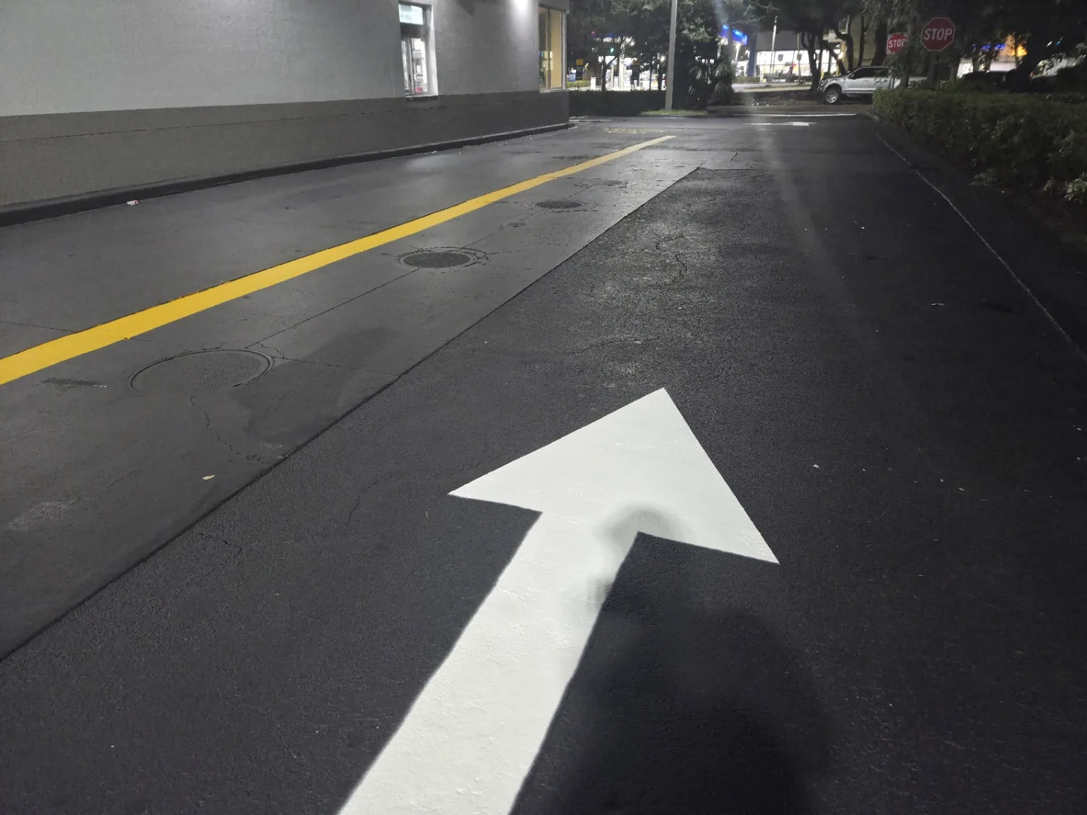Fresh directional arrow on commercial asphalt at night